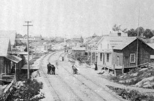 The old village of Sharbot Lake lined both sides of the tracks, with the first rail station on the right (with verandah). Mathew and Elizabeth Streets are named for the owners of a rooming house in the old village, Mathew and Elizabeth Garrett.